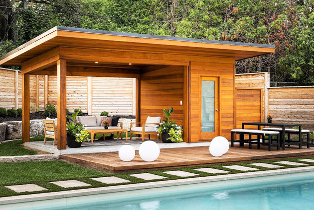 Poolside cabana with outdoor furniture accessories and wooden fence surrounding the perimeter.